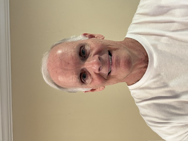 Dr. Wilson, smiling, wearing a white T-shirt
